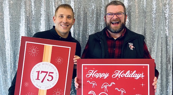 Two staff members taking a picture in a holiday-themed photo booth