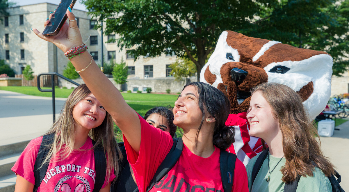 Four students take a selfie with Bucky Badger