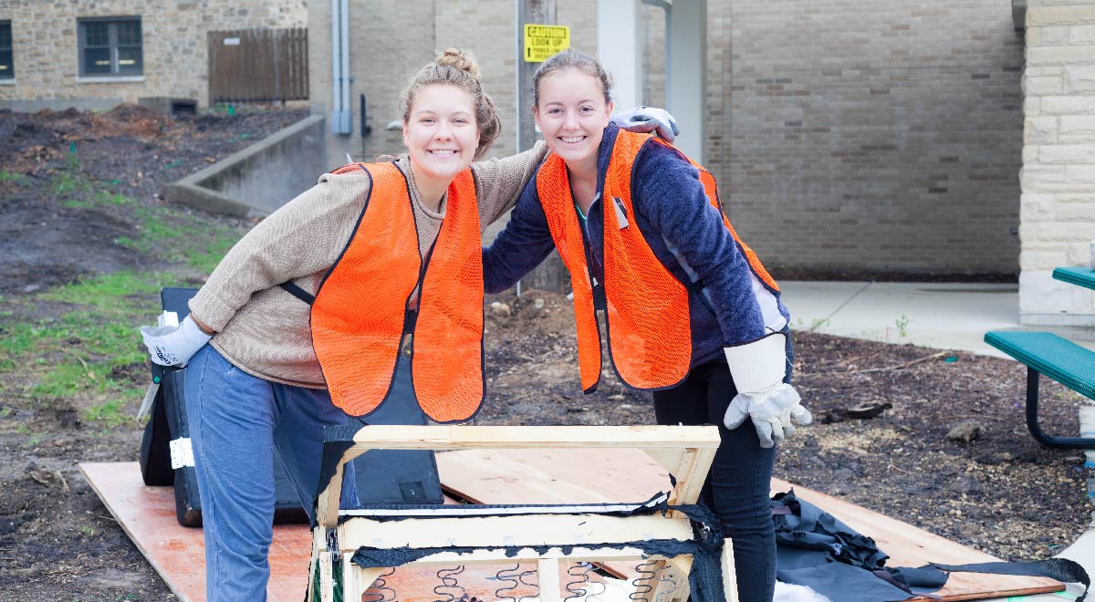 Two students helping recycle an unwanted futon