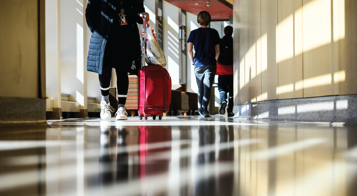 Students walk down the hallway at Dejope Residence Hall with suitcases
