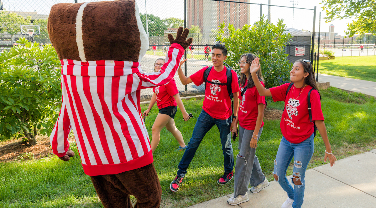 Bucky Badger high-fives three students on a summer day in the lakeshore neighborhood