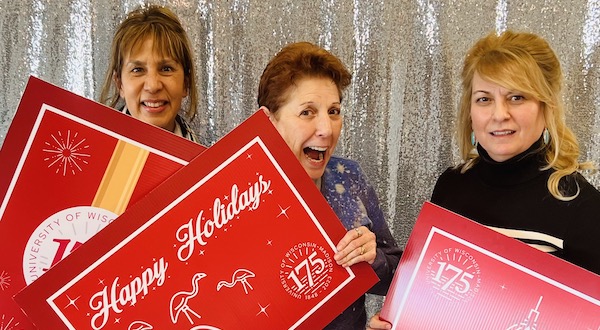 Three staff members taking a picture in a holiday-themed photo booth
