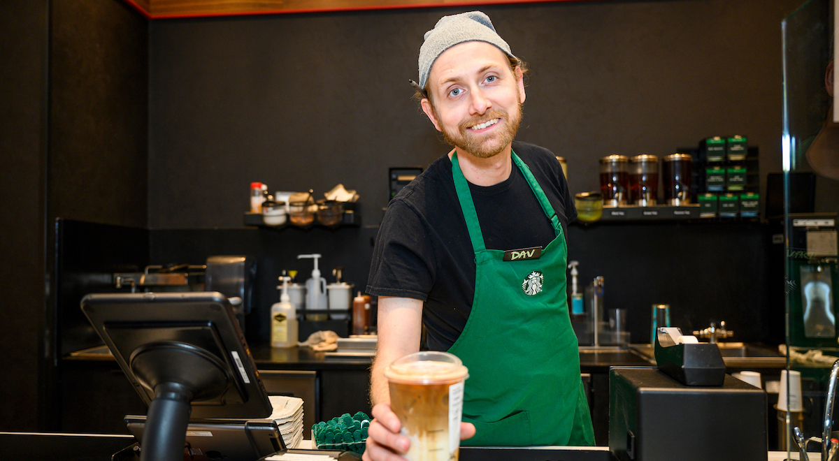 Starbucks staff member holding a coffee drink