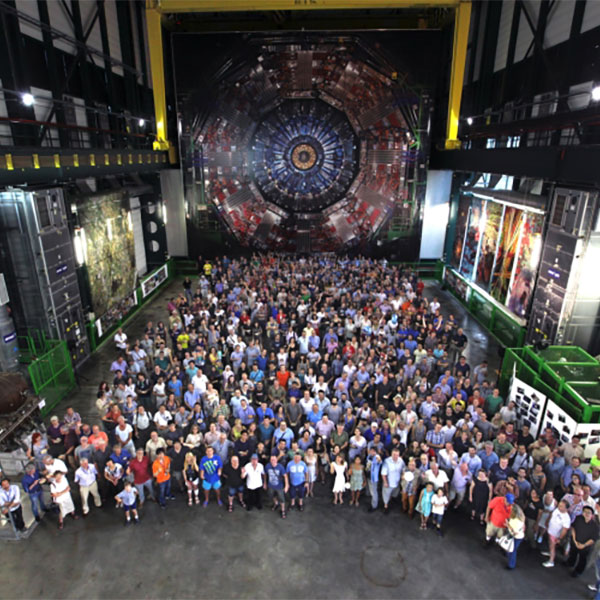 Over 100 scientists posing for photo with Collider in background