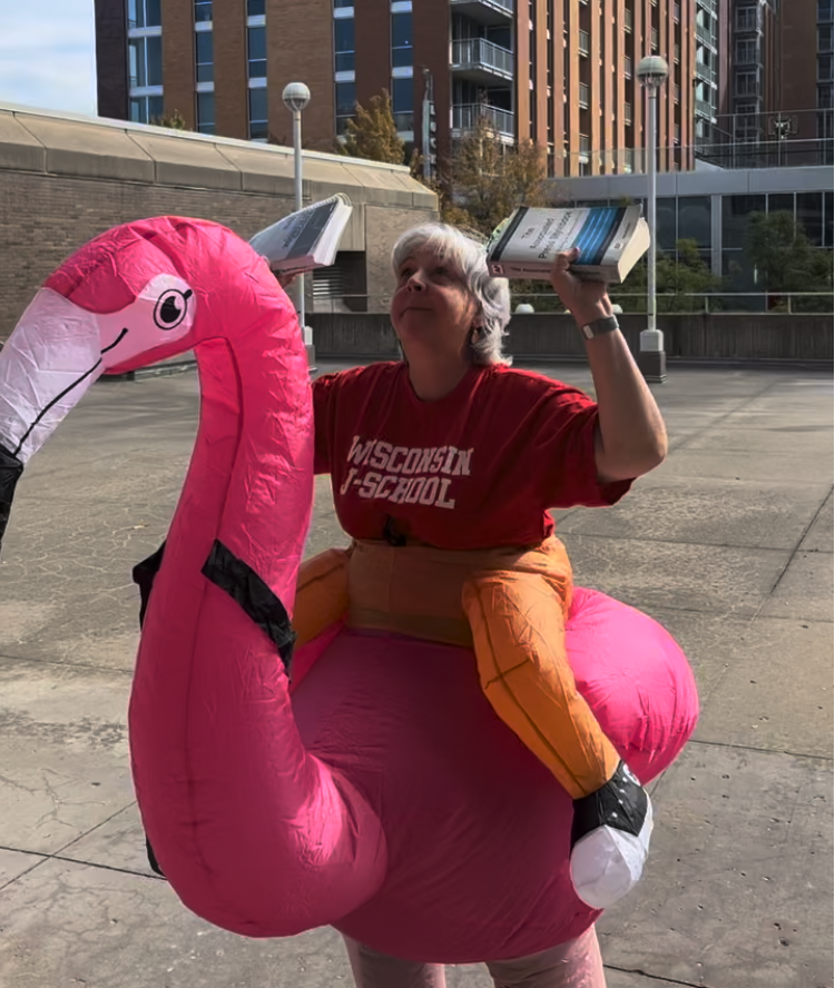 Katy Culver does benchpresses with AP Style books while wearing a flamingo costume