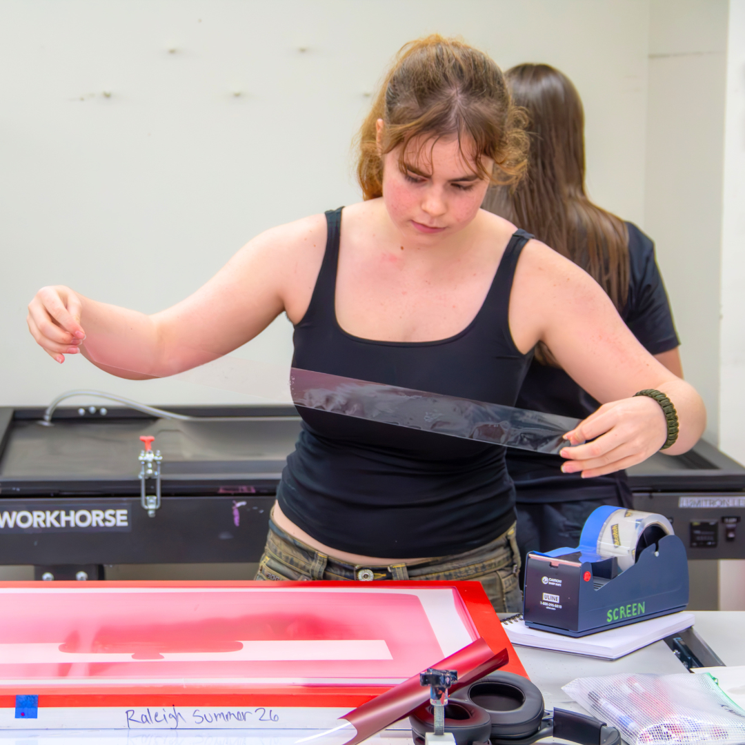Raleigh Savage in the printmaking workshop setting tape for a print.