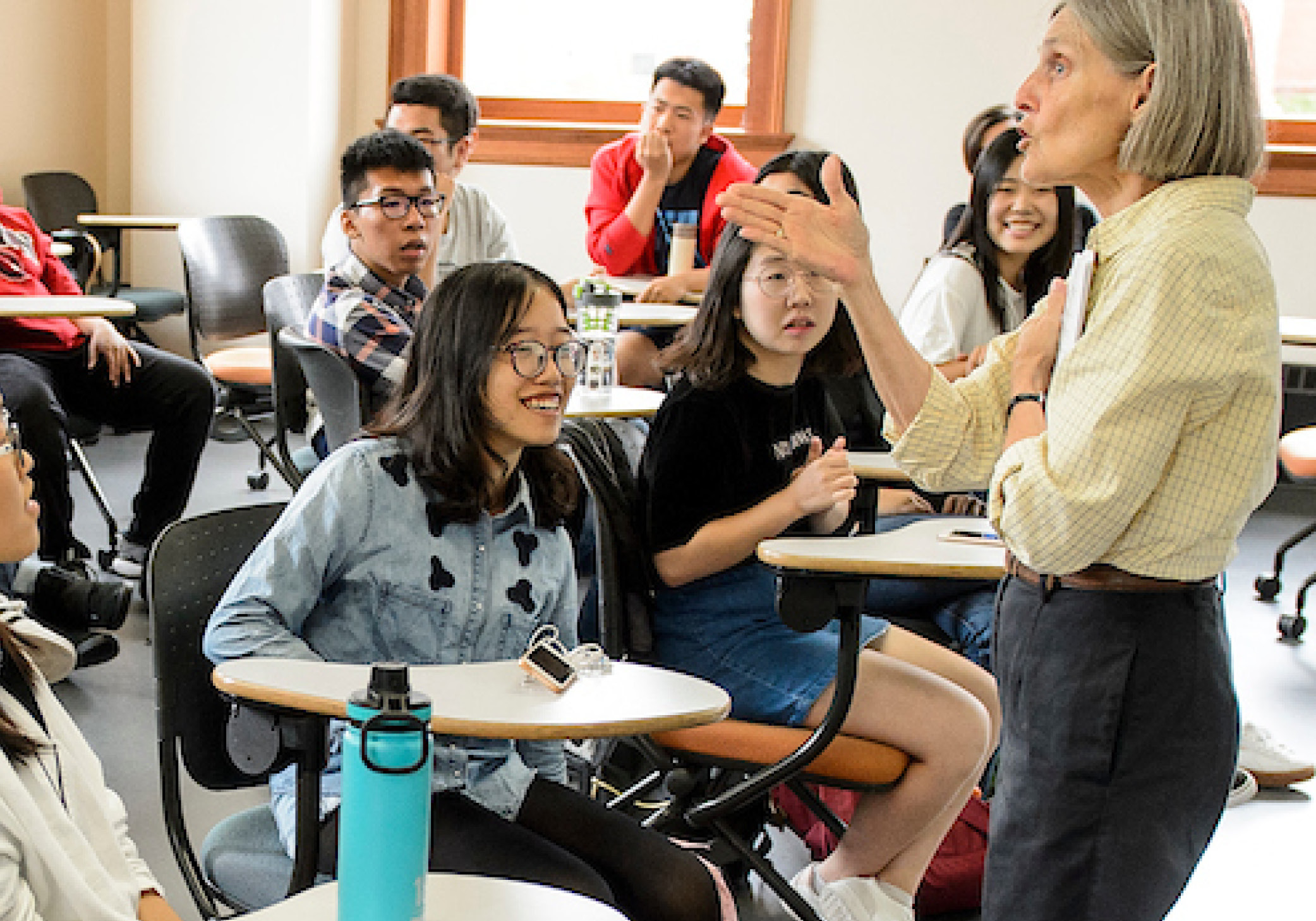 An instructor talks to a group fo students seated in chair desks.