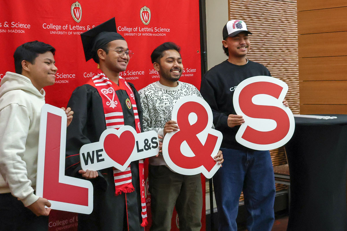 L&S Graduates pose with friends holding We love L&S signs