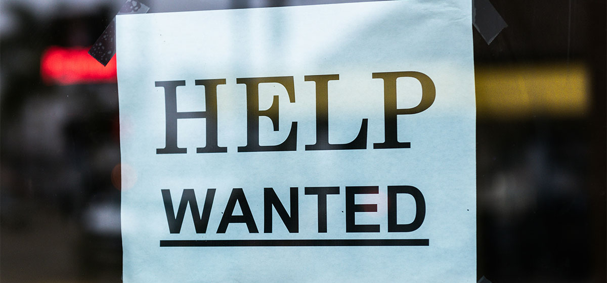 A help wanted sign posted in a window.