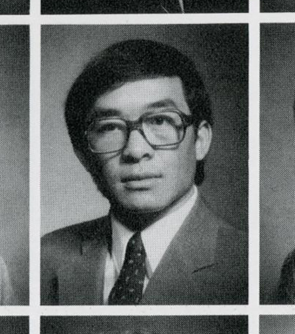 A black and white yearbook photo of a man with glasses wearing a suit and tie