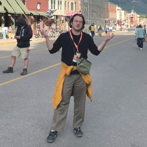 Image of graduate student Max Kaplan posing in front of a sign for the Telluride Film Festival