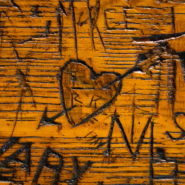 A heart with an arrow through it among names carved into a Rathskeller table
