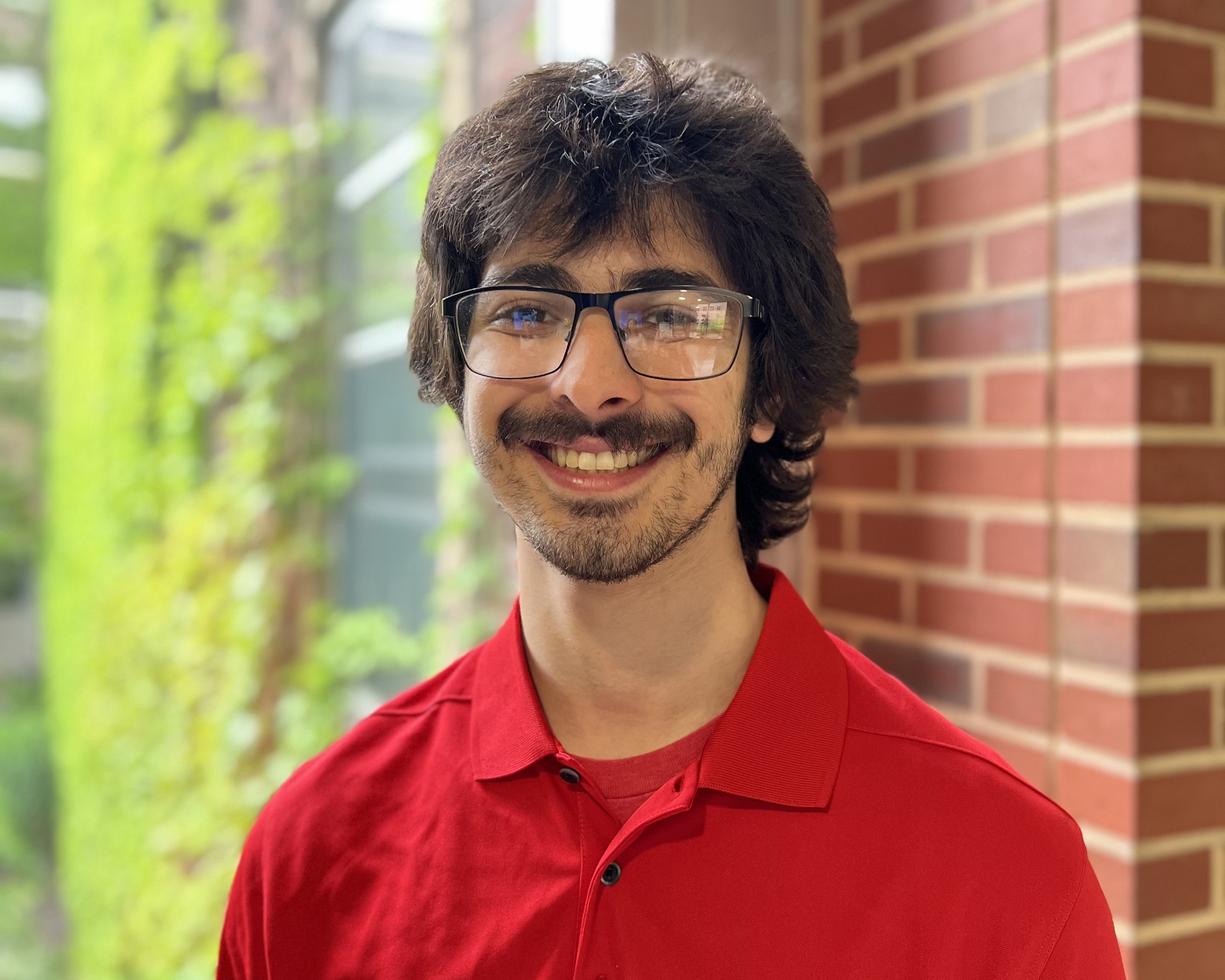 Sabeel Abuhakmeh smiles. He wears a bright red polo.