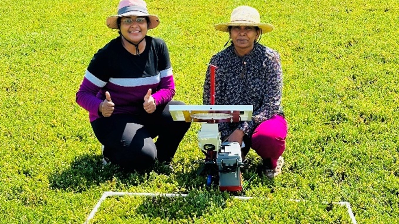 Dharani Suresh Babu and Jyostna Mura sit in a field.