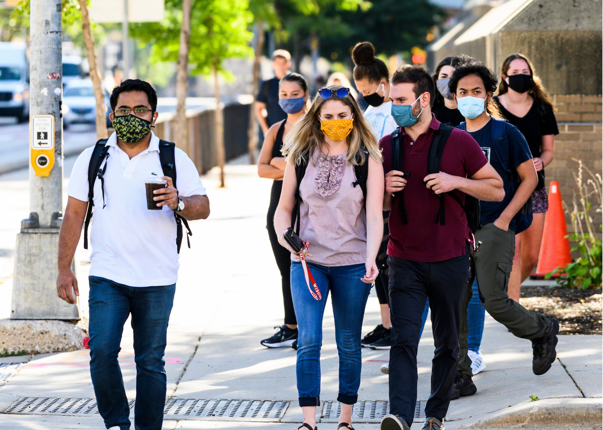 Students wear masks and walk down the sidewalk.