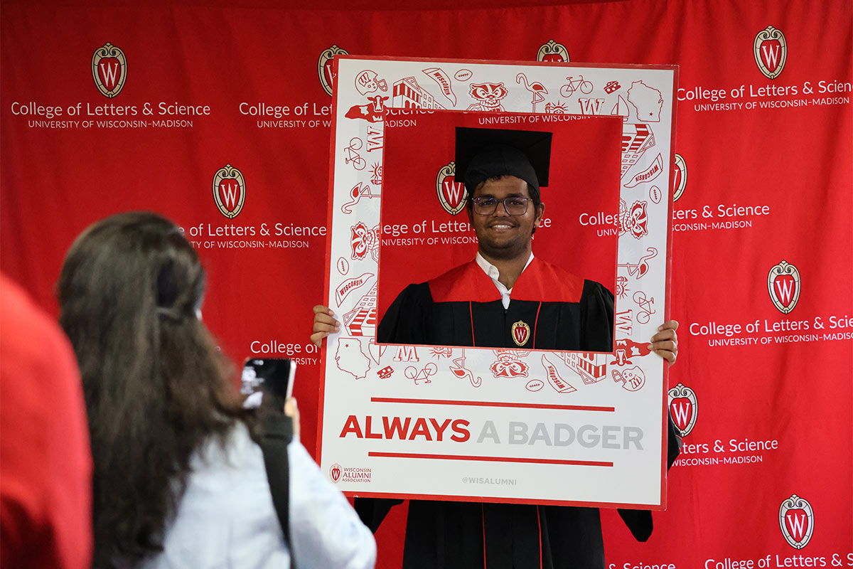 L&S Graduate posing against L&S backdrop photobooth 