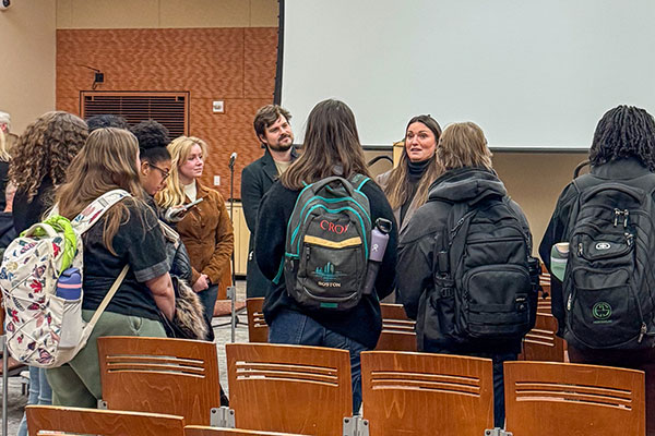 A woman talks to a group of students wearing backpacks