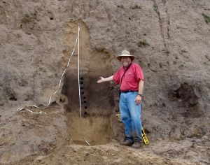 Man stands next to large rock formation