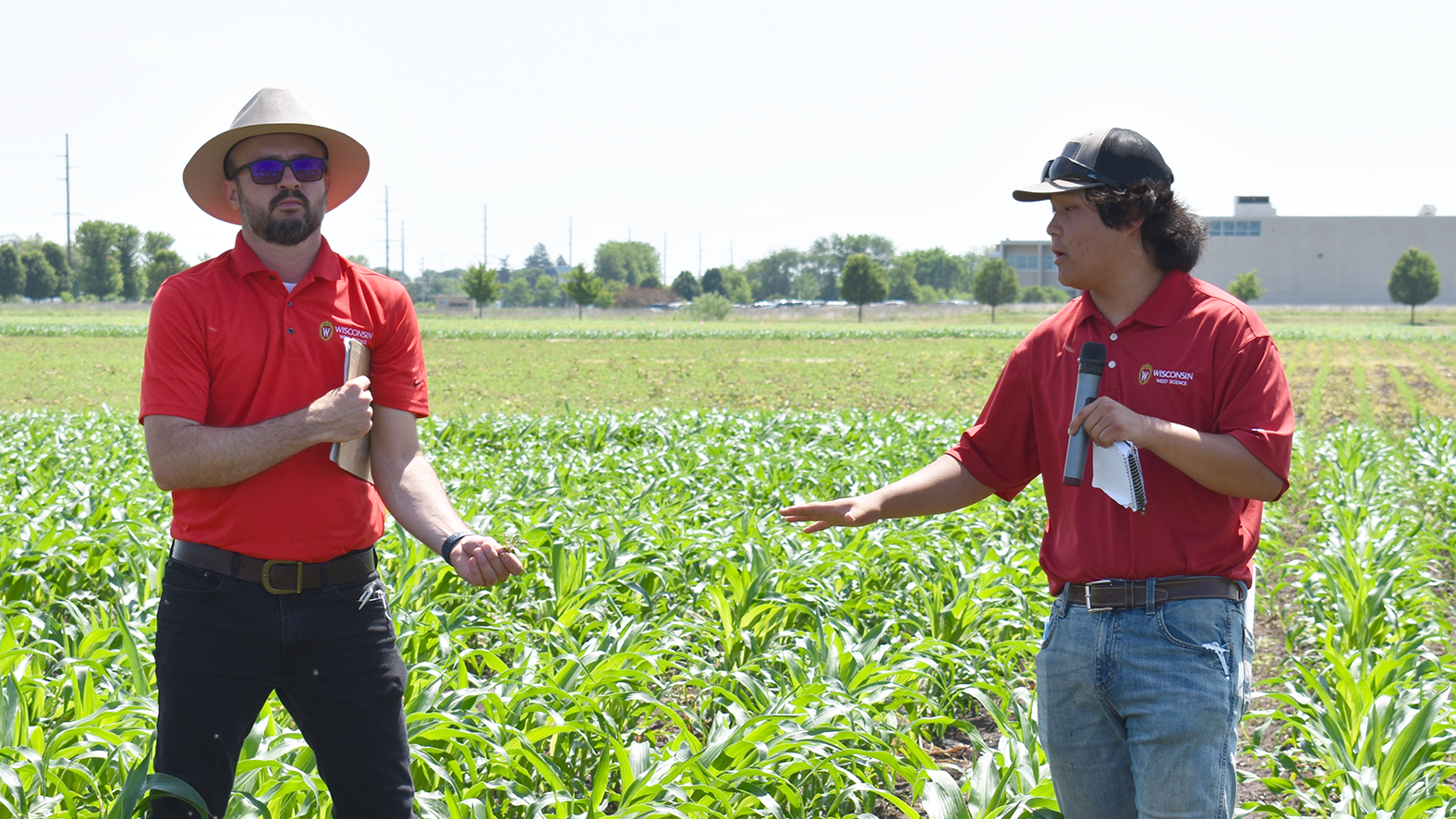 Two people stand in a field. They both wear red polos.