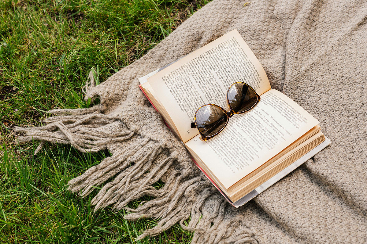 Book and sunglasses on picnic blanket