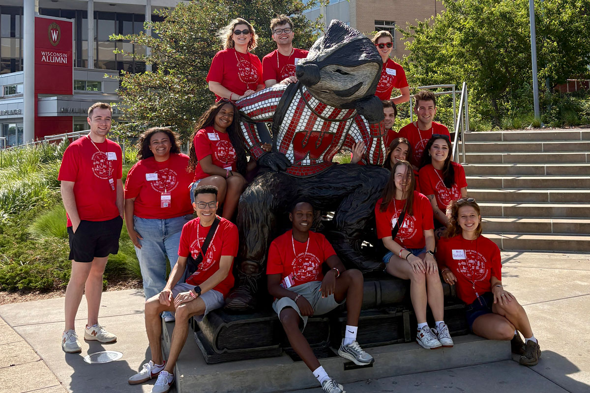 Recent Grads posing on Memorial Union Bucky Badger statue during the 2026 Revent Grad Weekend event. 