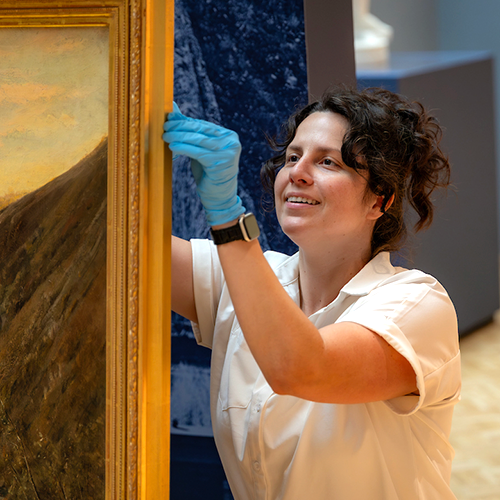 Exhibition and collection project manager Kate Wanberg handles a large painting.