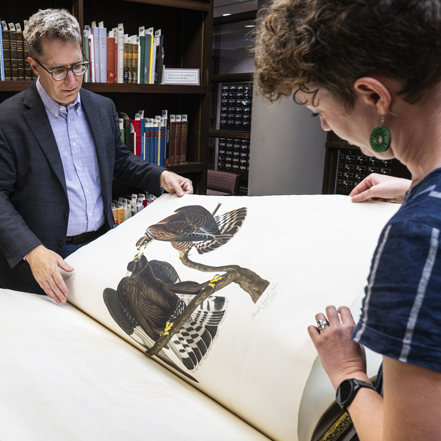 Associate Dean David Pavelich and librarian Emily Spunaugle examine a historical book.
