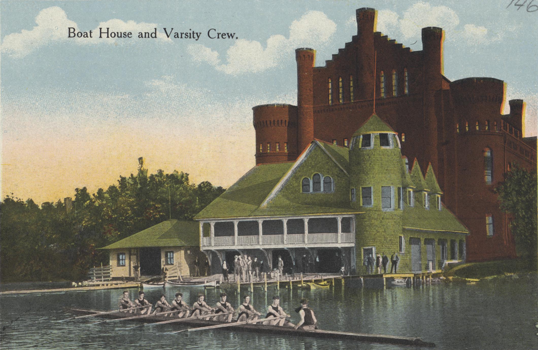 A colorized photo with a crew team rowing on a lake in front of a green boathouse and red brick gym building