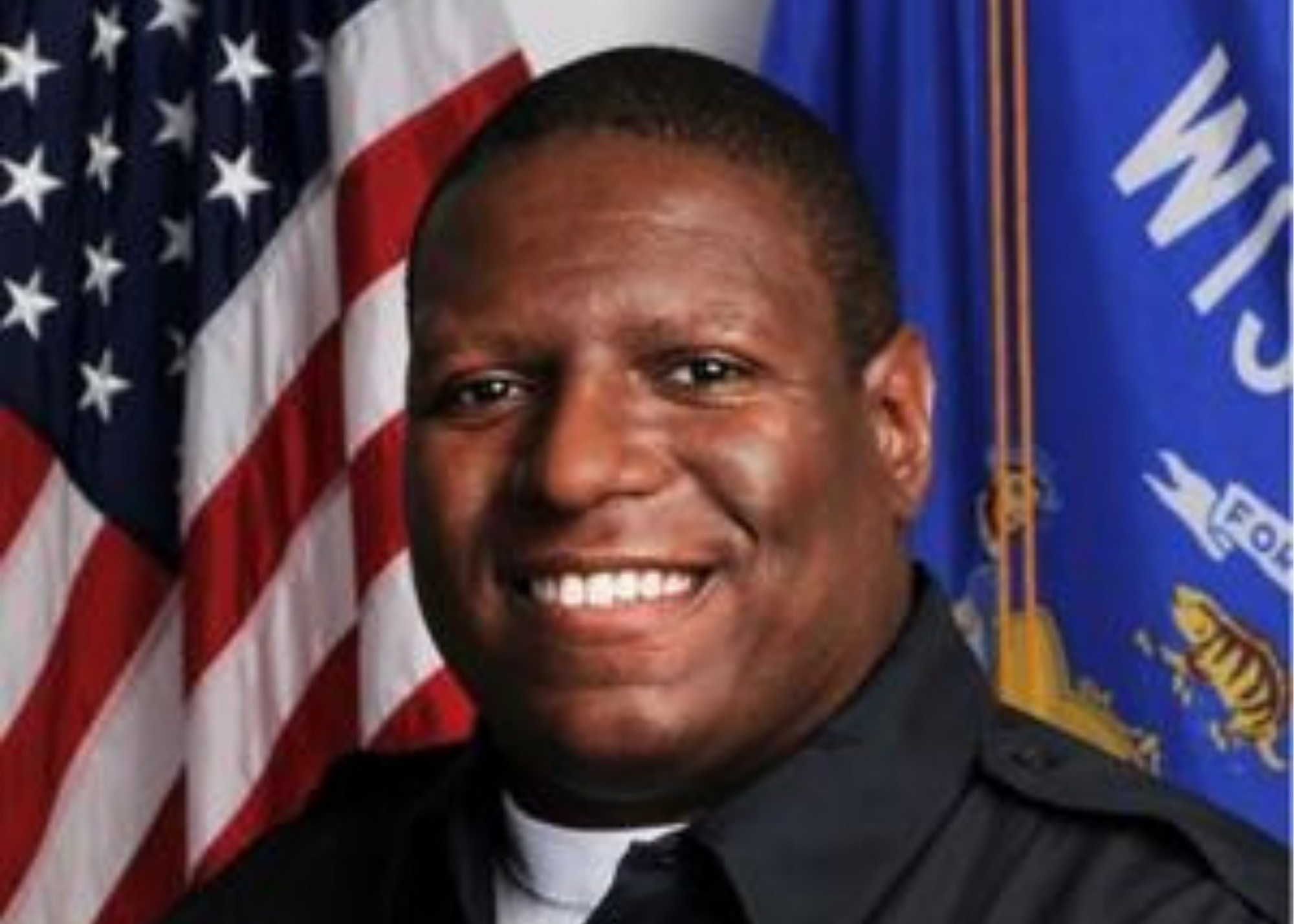 A professional photo of Kalvin Barrett in uniform in front of a Wisconsin flag and a United States flag.