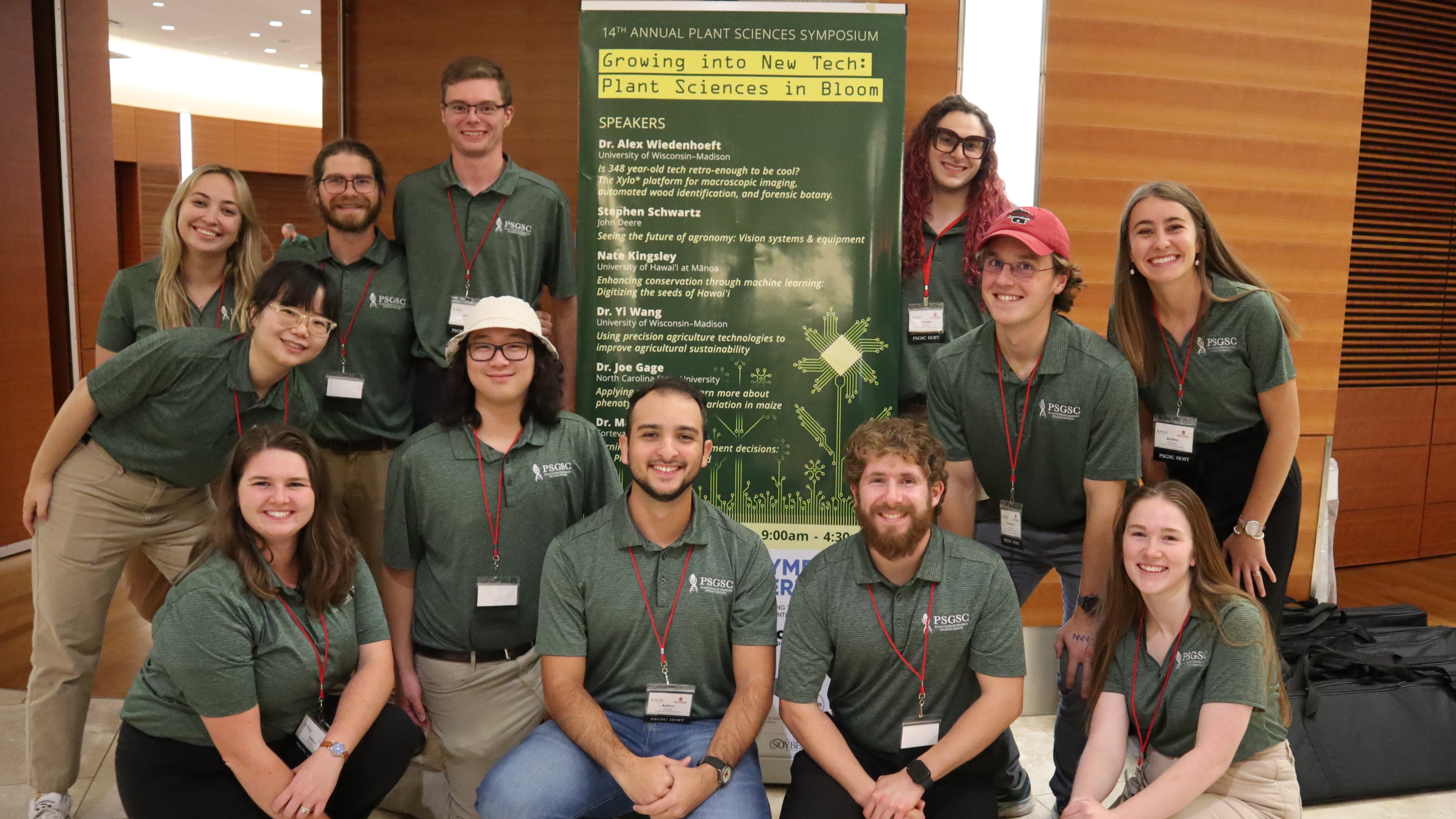 A group of people wearing forest green polos gather for a photo.