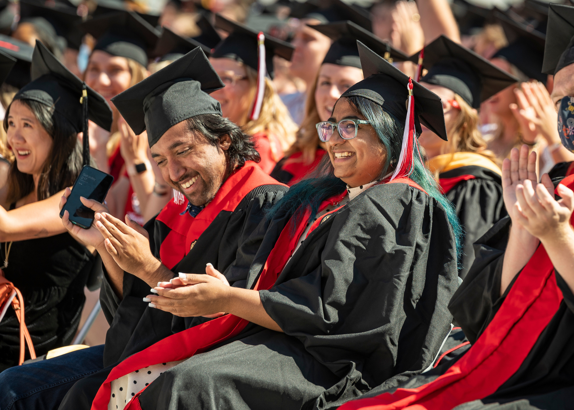 Several graduates wearing their caps smiling in the audience at the ceremony.