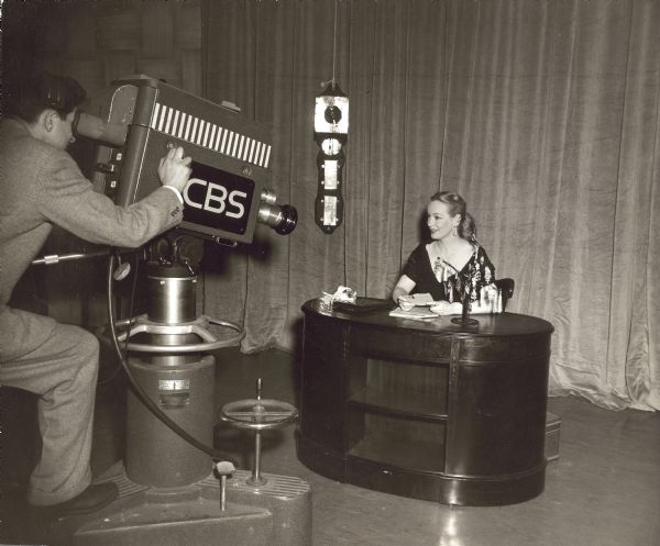Faye Emerson sits at a desk facing a CBS camera.