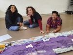 Three students sit behind a fabric map