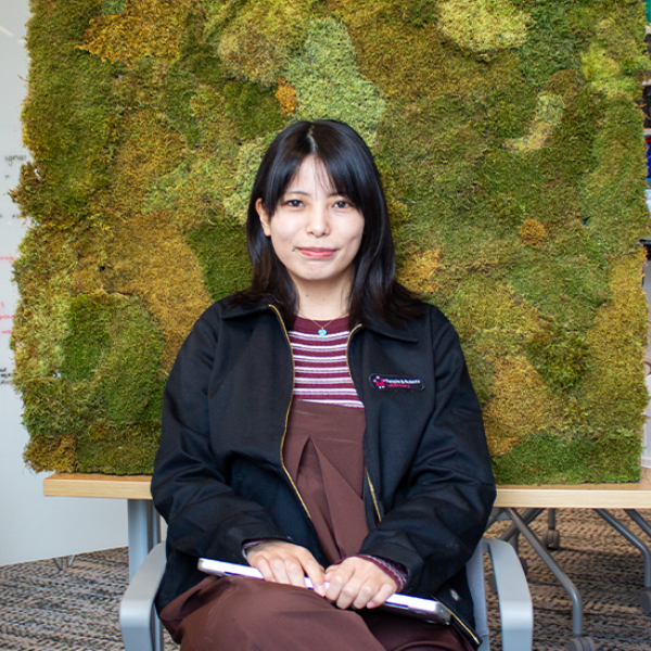 Amy Koike in front of a green wall.