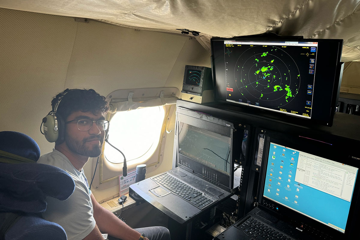 Nikhil Trivedi sitting at a storm monitoring station inside an airplane. 