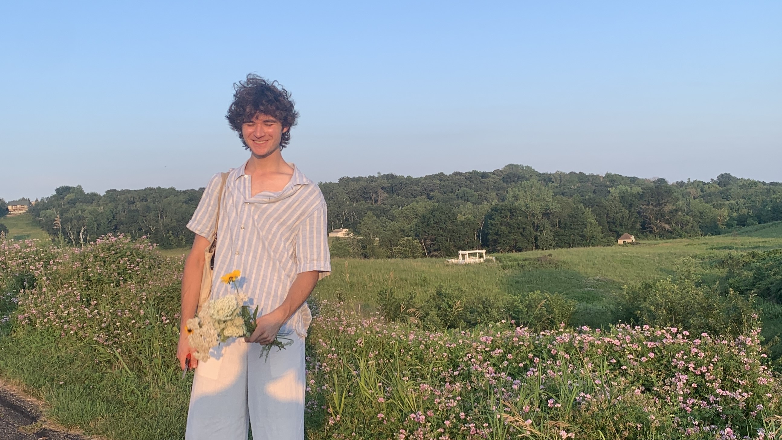 Mason stands in a field with a bouquet of flowers.