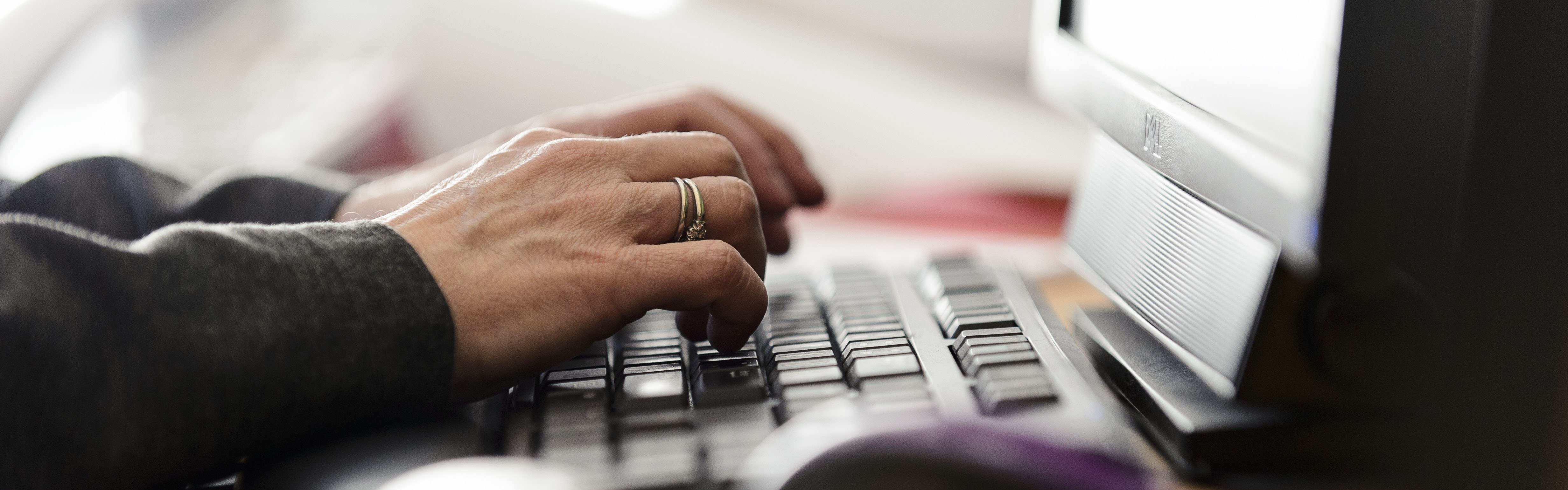 Photograph of hands typing on computer keyboard