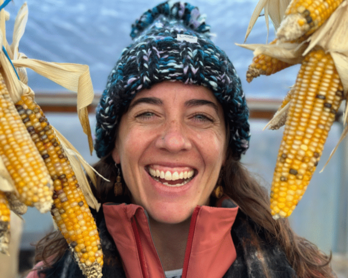 Cathleen McCluskey smiles and holds up maize.