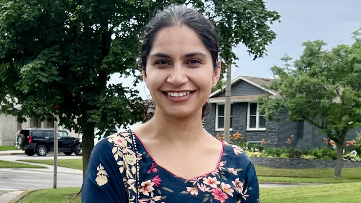 Dr. Kaur smiles with a street in the background.