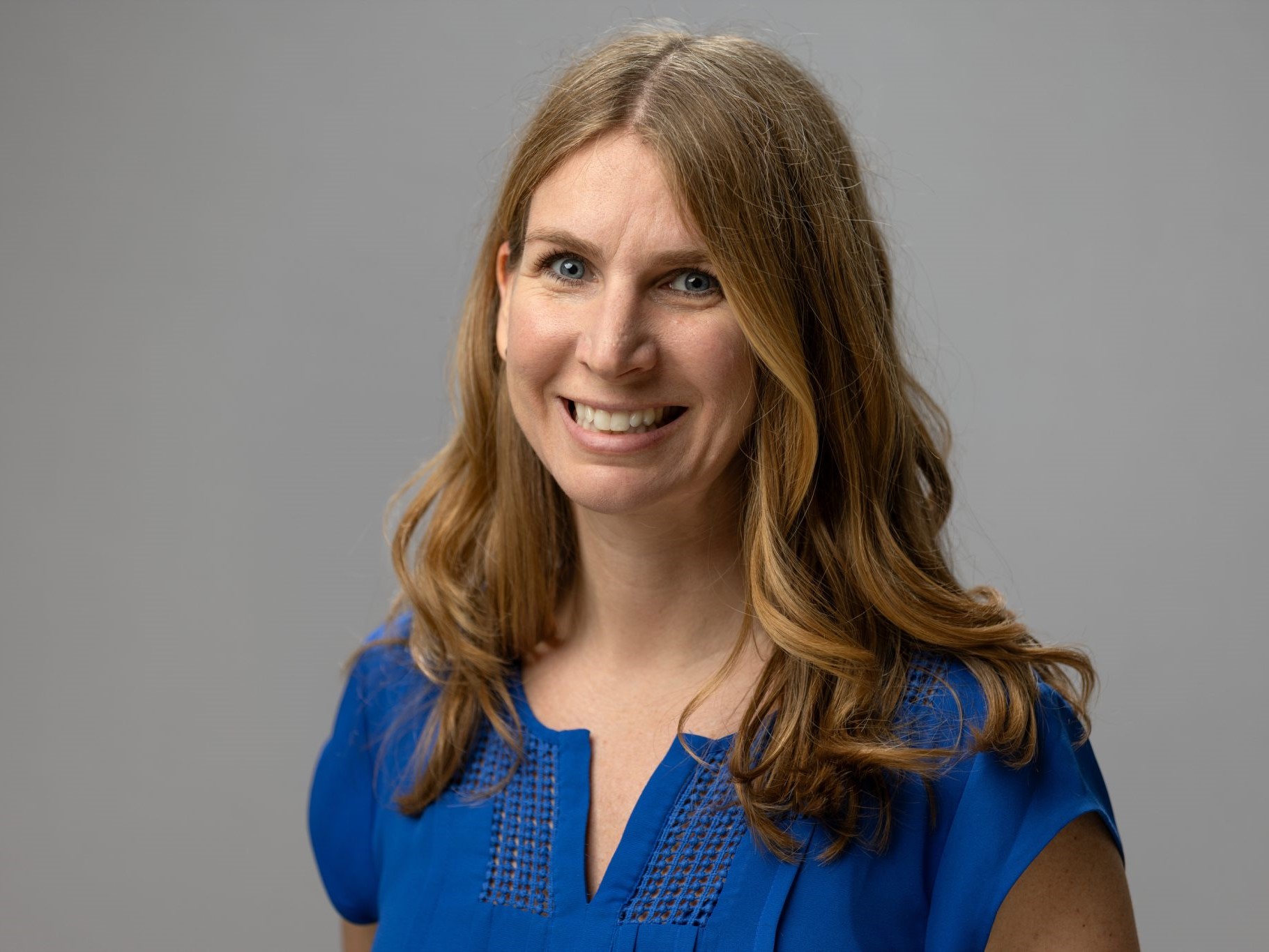 Dr. Ellison smiles in front of a grey backdrop.