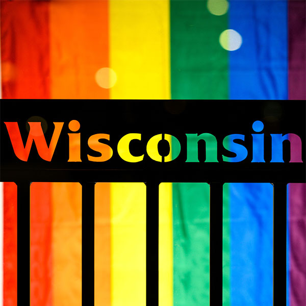 Wisconsin cutout sign with Pride flag behidn it.