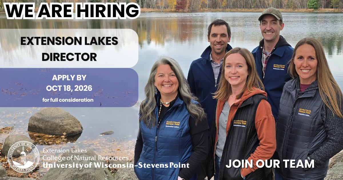 five smiling staff members wearing vests and jackets with a University of Wisconsin Stevens Point Extension Lakes logo in the upper left pocket area. a calm lake lined with trees in fall colors is in the background. The words "WE ARE HIRING Extension Lakes Director Apply by October 18, 2026 for full consideration" and "Join our team" are superimposed on the photo.